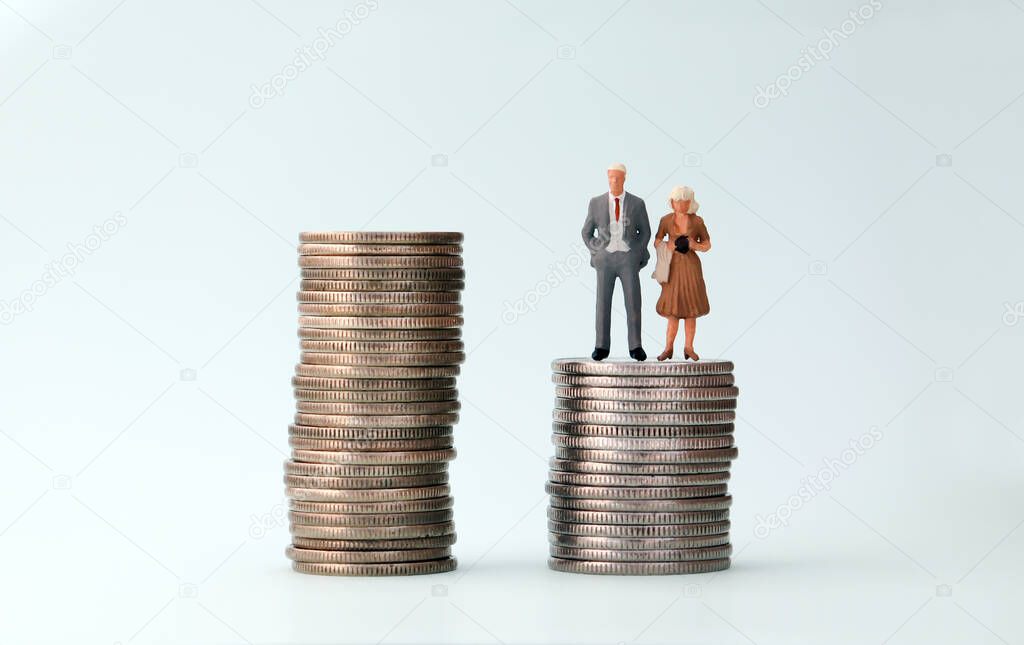 A miniature man and a miniature woman standing in a pile of small coins.
