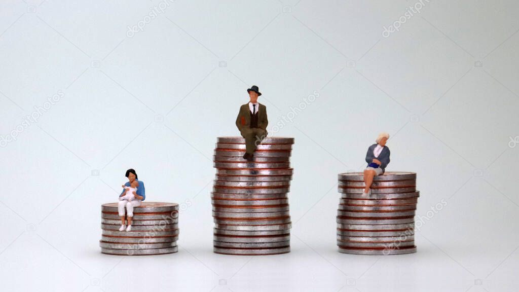 The concept of a wage gap between men and women. A pile of coins and miniature people.