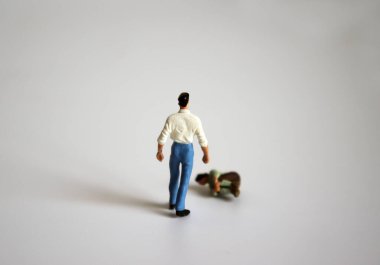 Aile içi şiddet kavramı. Minyatür bir adam ayakta duruyor ve minyatür bir kadın düşüyor..