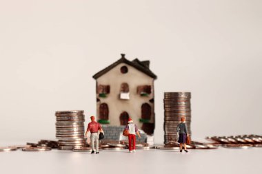 Minyatür ev ve bozuk para yığınları. Bir yığın bozuk para ve minyatür insan.. 