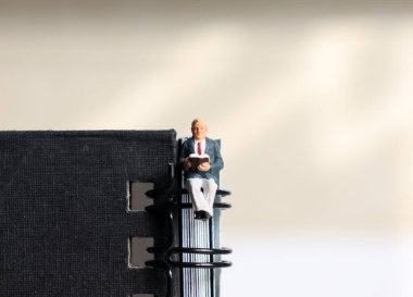 Bir minyatür adam, bir nota ringinde oturmuş kitap okuyor..