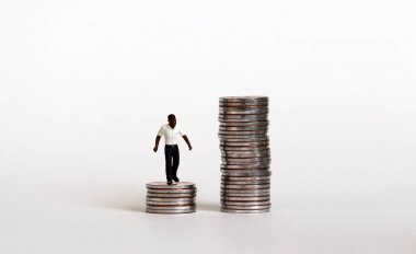 Irksal ücret ayrımcılığı kavramı. Bozuk paraların üzerinde duran minyatür siyah bir adam..