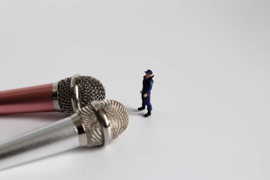 Minyatür bir polis memuru iki mikrofonun önünde duruyor..