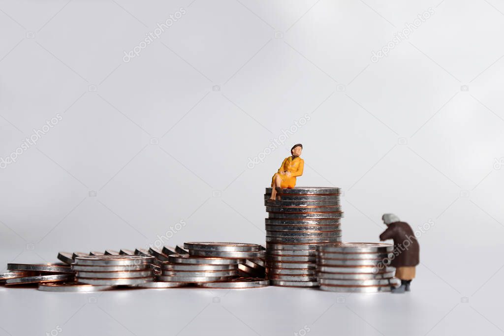 A miniature woman holding a pile of coins and a miniature woman sitting on a pile of coins.