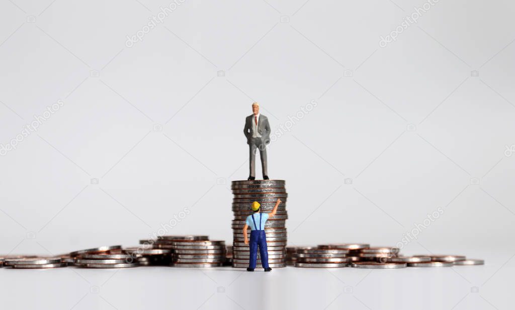 Miniature people and coins. The concepts of antagonism between the employer and the employed.