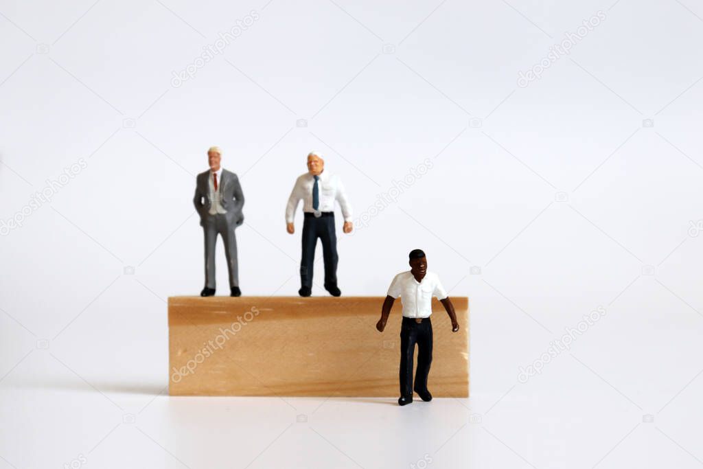 Miniature people standing on tree blocks and miniature man standing under tree blocks.