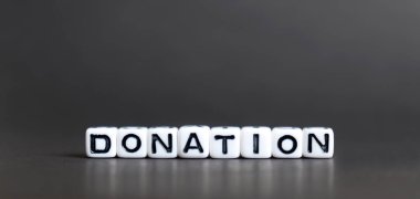Siyah arkaplanda DONATION harfleri olan alfabe küpü.