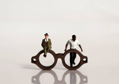 Miniature people and miniature glasses. The concept of racial prejudice and discrimination. clipart