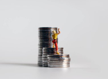 Minyatür bir kadının sırtında bir yığın bozuk paraya tırmanıyor..