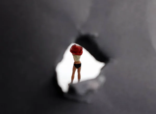 Miniature woman. The back of a woman who is changing her clothes that are seen through a small hole.