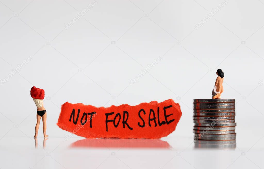 NOT FOR SALE message on the ripped paper. Stop selling people. Miniature women with the pile of coins.