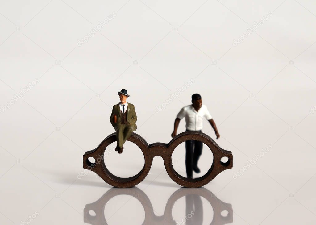 Miniature people and miniature glasses. The concept of racial prejudice and discrimination.