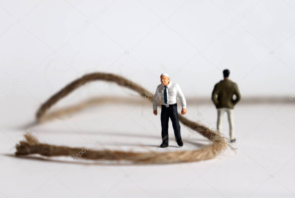 Two miniature men standing on either side of the rope. The concept of intergenerational discord.
