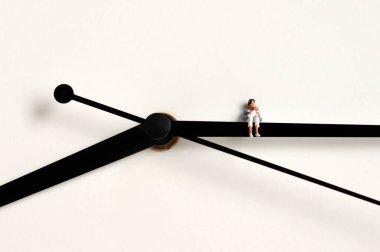 Elinde bebekle oturan minyatür bir kadın..