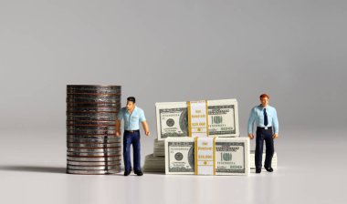 Bir yığın banknot ve bozuk para. Minyatür insanlar. Ekonomik eşitsizlik kavramı.