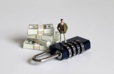 Kilidin üzerinde duran minyatür bir adam ve bir yığın banknot..
