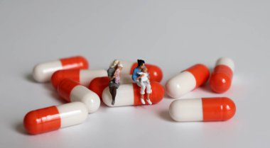 İki minyatür kadın bir kapsülde oturup bebek tutuyorlar..