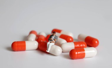 Minyatür bir adam kapsülde oturuyor ve elinde bir bebek var..