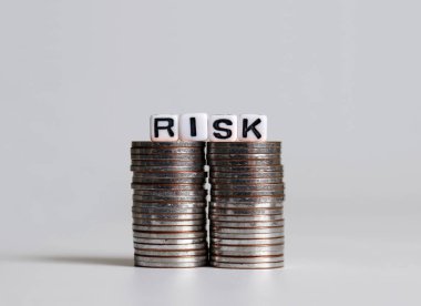 'RISK' metni iki bozuk para yığını üzerinde beyaz küp.