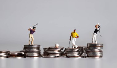 Bozuk paraların üzerinde duran minyatür golfçüler.