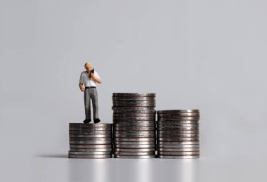 Bozuk para yığınlarının üzerinde minyatür bir adam..