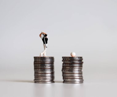 Bozuk paraların üzerinde golf oynayan minyatür insanlar..