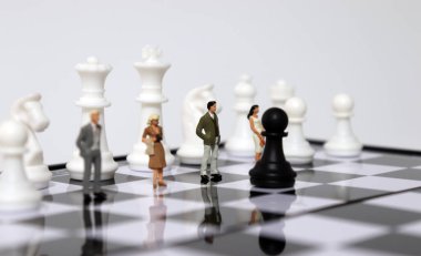 Satranç tahtasında satranç taşlarıyla duran minyatür insanlar. İş krizi kavramı..