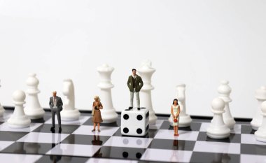 Satranç atları ve minyatür insanlar. Zarın üzerinde duran minyatür bir adam.