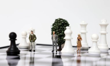 Satranç tahtasında duran minyatür insanlar ve satranç taşları. Başarılı strateji kavramları.