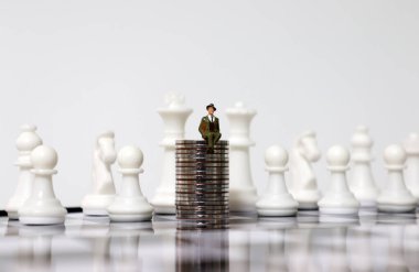 İçinde madeni para ve minyatür insanlar olan bir satranç tahtası..