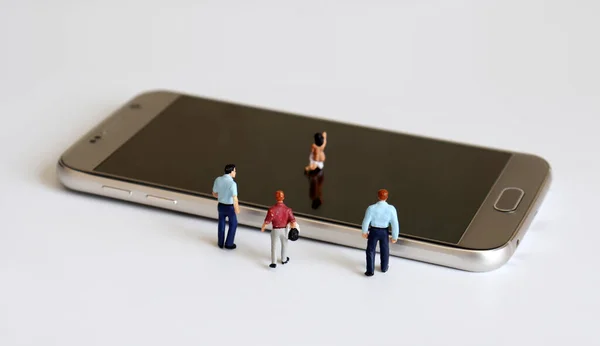 Smartphone and miniature people. The concept of secretly leaking cameras.