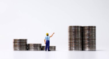 Merdiven şeklinde para yığınları ve kule şeklinde para yığınları. Bir yığın bozuk parayı işaret eden minyatür bir adamın arkası..