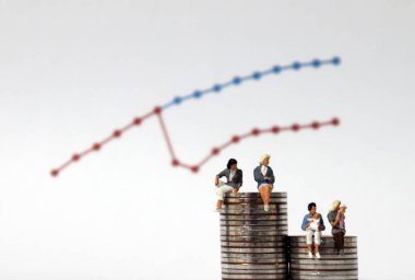 Farklı yüksekliklerdeki bozuk paraların üzerinde oturan minyatür kadınlar. Kadınların doğum ve maaş farkları kavramı.