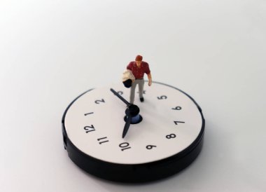 Saatin üzerinde yürüyen minyatür bir adam. Zaman işi kavramı..