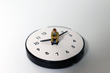 Saat iğnesinde oturan minyatür bir adam. Zaman yönetimi kavramı.
