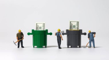 Minyatür insanlar ve içinde yüz dolarlık banknotlar olan iki çöp kutusu.. 