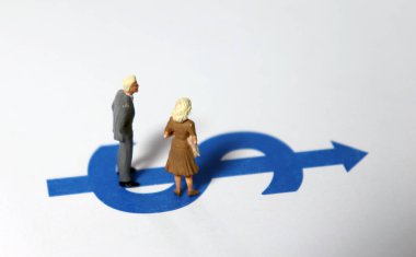 Minyatür bir adam ve minyatür bir kadın dolar işaretinin üzerinde duruyorlar..