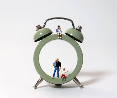 Çalar saat ve çocuğun yanındaki minyatür insanlar..