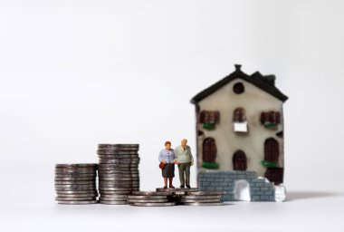 Minyatür bir evde bozuk para yığını üzerinde yaşlı bir çift..