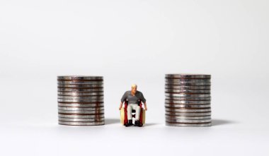 İki bozuk para yığını arasında tekerlekli sandalyede minyatür bir adam..