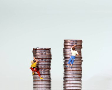 Minyatür insanlar bozuk para yığınına tırmanıyorlar. Bir iş yarışması konsepti.