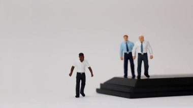 Terfi ederken ırk eşitsizliği kavramı. Farklı ırklardan minyatür insanlar..
