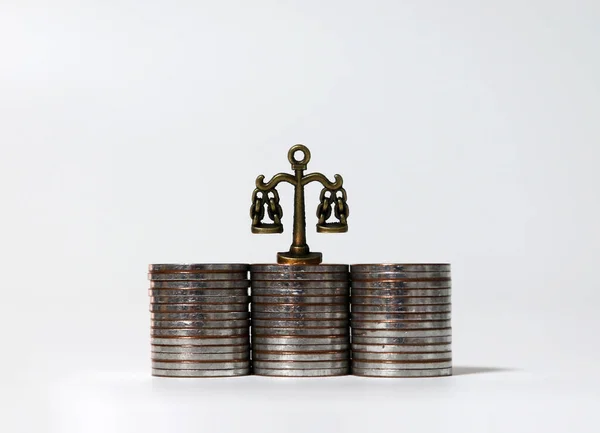 Miniature scales on top of three coin piles.