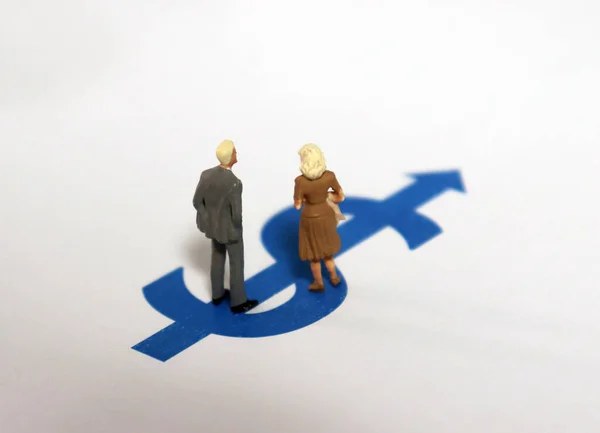 A miniature man and a miniature woman standing on the dollar sign.