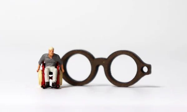 Homem Miniatura Uma Cadeira Rodas Frente Óculos Miniatura Madeira — Fotografia de Stock