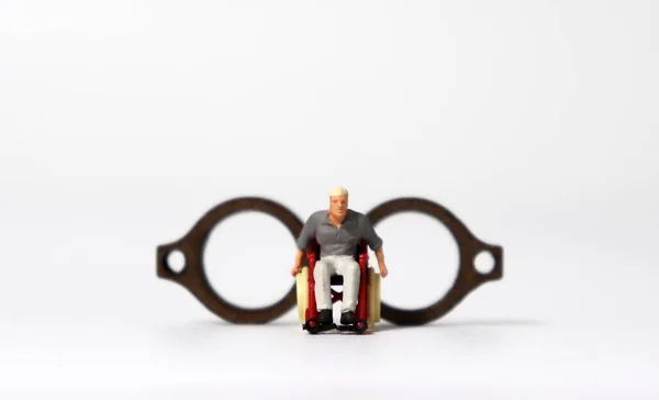 Ein Miniaturmann Rollstuhl Vor Einer Hölzernen Miniaturbrille — Stockfoto