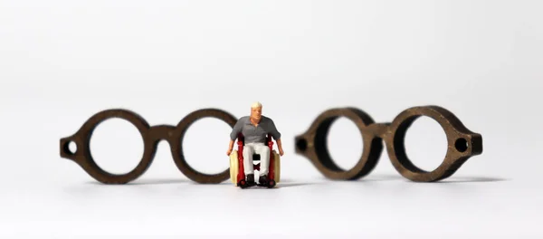 Homem Miniatura Uma Cadeira Rodas Frente Dois Óculos Miniatura Madeira — Fotografia de Stock