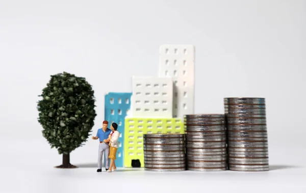 Ein Miniaturpaar Steht Vor Einem Miniaturgebäude Mit Einem Haufen Münzen — Stockfoto