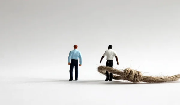 stock image A concept of racial prejudice. Two miniature men and rope.