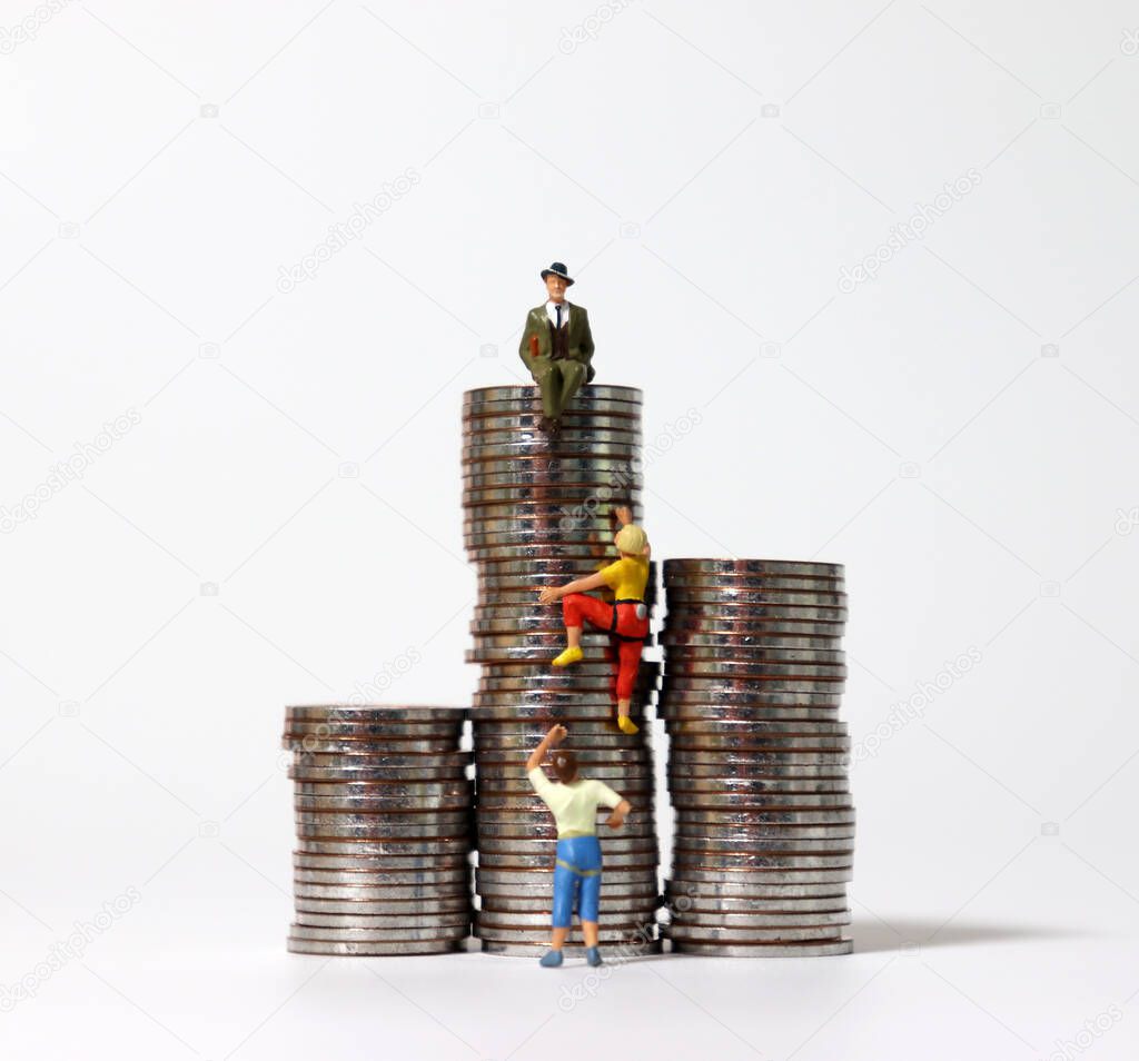 Miniature people climbing the highest pile of coins